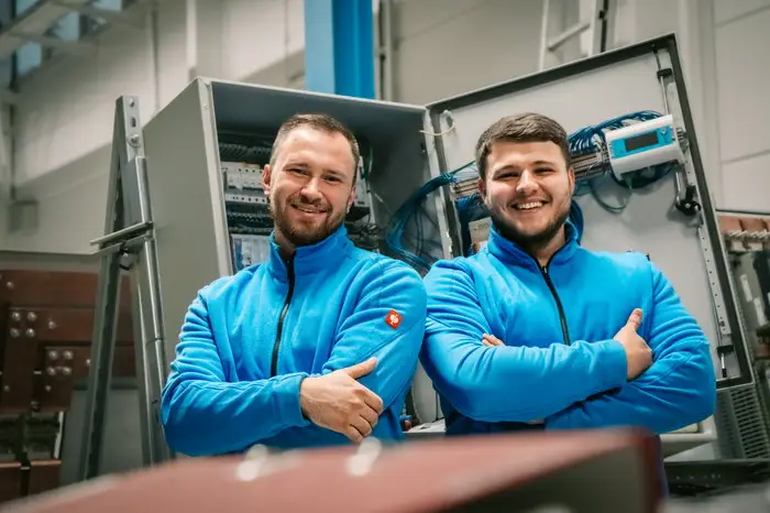 Zwei lächelnde Mitarbeiter der Faber E-Tec GmbH in blauer Arbeitskleidung
