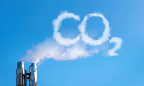 Industrieller Schornstein mit CO₂-Schrift aus Rauch – Symbolbild für Emissionen und CO₂-Reduzierung durch BESS-Batteriespeicher von Faber E-Tec