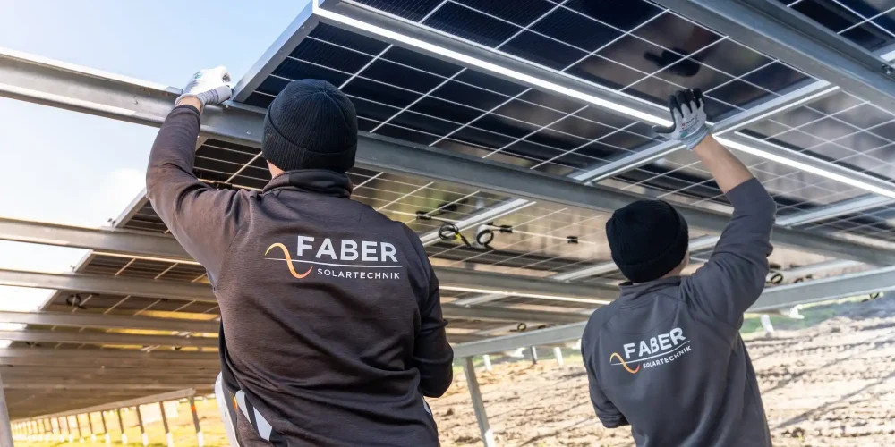 Zwei Monteure von Faber Solartechnik installieren Solarmodule auf Gestell